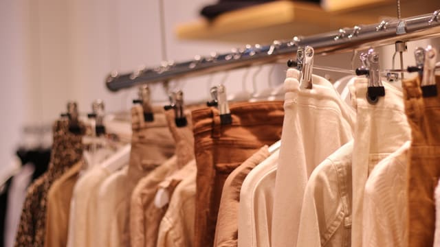 Neutral-colored clothes hanging on a rail.
