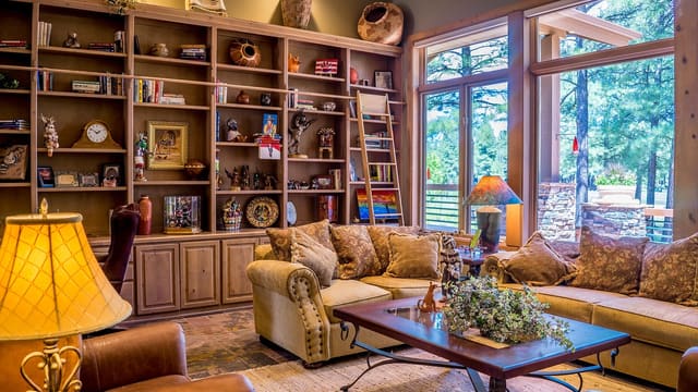 A warm living room with bookshelves and large windows.
