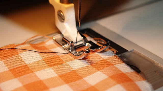 A sewing machine stitching checked fabric.